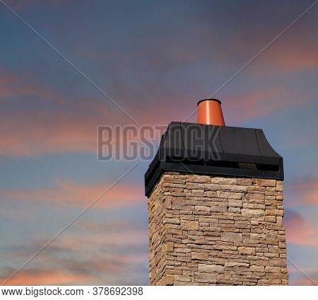 Stone Chimeny With Metal Cap Afainst A Clear Blue Sky