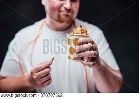 Chubby Man In A White Duffle, Eating French Fries With Sauce With A Big Pleasure