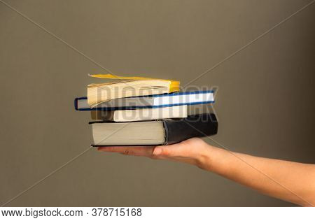A Stack Of Books In Your Hand, A Day Of Books, Several Books On One Hand On A Neutral Background. Ho