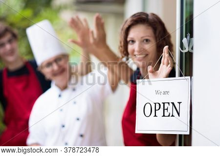 Cafe Opening After Lockdown. Open Sign On Front Door Of Restaurant Or Grocery Store. Waiter In Apron