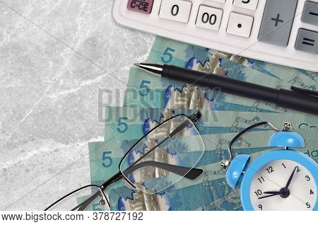 5 Canadian Dollars Bills And Calculator With Glasses And Pen. Business Loan Or Tax Payment Season Co