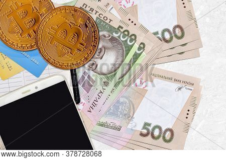 500 Ukrainian Hryvnias Bills And Golden Bitcoins With Smartphone And Credit Cards. Cryptocurrency In