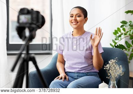 blogging, videoblog and people concept - happy smiling african american female video blogger with camera videoblogging at home