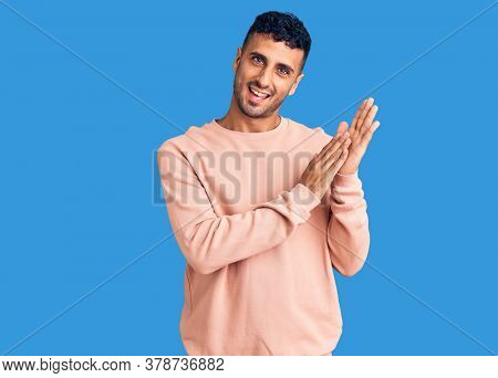 Young hispanic man wearing casual clothes clapping and applauding happy and joyful, smiling proud hands together 