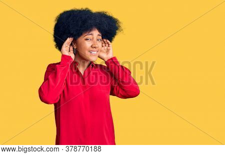 Young african american girl wearing casual clothes trying to hear both hands on ear gesture, curious for gossip. hearing problem, deaf 