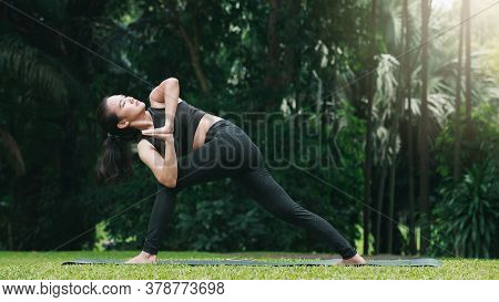Asian Woman Practicing Yoga In Prep Poses For Side Crane Pose For Parsva Bakasana On The Mat In Outd