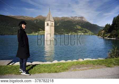 Traveler Thai Woman Travel And Posing Take Photo At Submerged Tower Of Reschensee Church Deep In Res