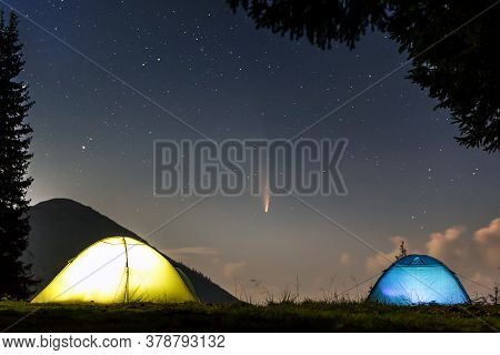 Two Brightly Lit Tourist Tents On Forest Clearing In Mountains With Starry Sky And C/2020 F3 (neowis