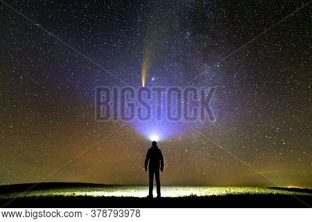 Silhouette Of A Man With Flashlight On His Head Pointing Bright Beam Of Light On Starry Sky With Neo