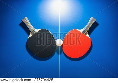 Top View Black And Red Table Tennis Racket And A White Ping Pong Ball On The Blue Ping Pong Table Wi