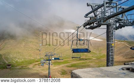 Close Up Of Cableway In Clouds. Clouds Enveloping Modern Ropeway With Benches In Amazing Mountainous
