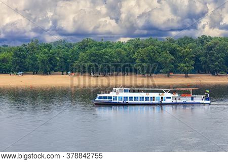 A River Tram With A Few Tourists Resting Goes Along The River Against The Backdrop Of Coastal Greene