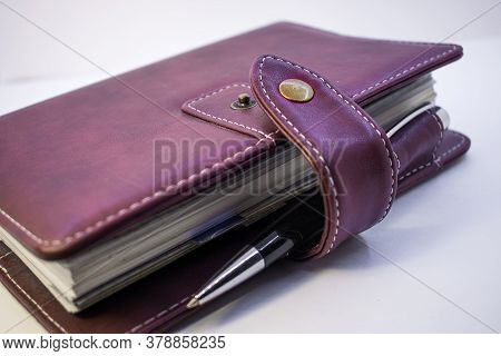 A Maroon Notebook With An Iron Clasp Lies On A Light Background