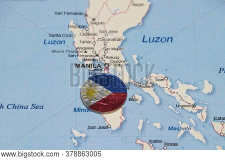 Pilipino Flag On The Coin Of Philippine One Peso Money On The Map Near Manila City. Concept Of Finan