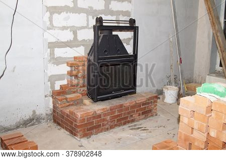 Black Cast Iron Firebox With A Lift Door Stands On The Brickwork In The Living Room