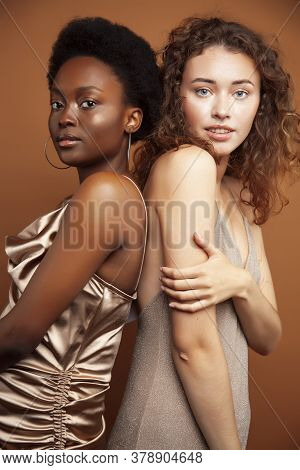 Two Pretty Girls African And Caucasian Blond Posing Cheerful Together On Browm Background, Etnithity
