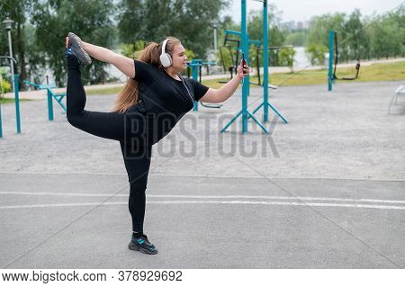 Beautiful Fat Young Woman In Headphones Makes A Figure Skater And Takes A Selfie. A Chubby Smiling G