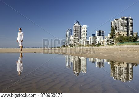 Man With Medical Mask Sitting On Beach During Coronavirus Covid 19 Pandemic, Social Distance Concept