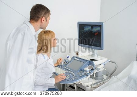 Two Doctors Looking At The Ultrasonography Divice In A Medical Office