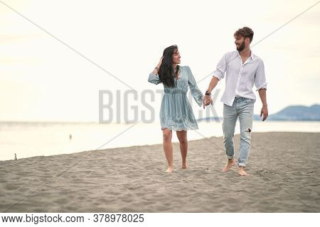 Happy couple holding hands in romanitic walk by the sea.