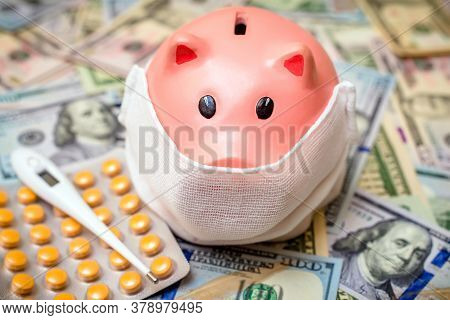 Piggy Bank In A Mask On A Background Of American Currency.the Concept Of Coronavrius Epidemic