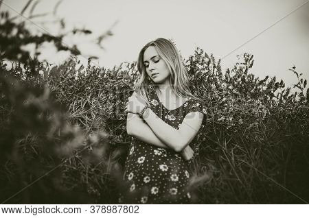 A Young Blonde European Thin Girl Stands In The Midst Of Very Tall Purple And Poppy Plant