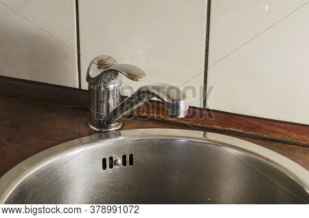 Round Stainless Steel Kitchen Sink With Mixer. Top View At An Angle Of Metal Sink. Sanitary Cleaning