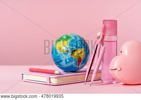 Pink Stationery With Blue Toy Globe On Pink Background With Diary Or Copybook. Office Or School Stat
