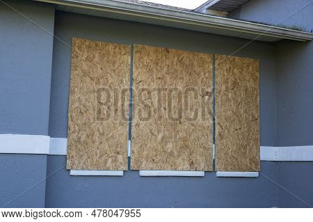 Boarded Up Windows With Plywood Storm Shutters For Hurricane Protection Of Residential House. Protec