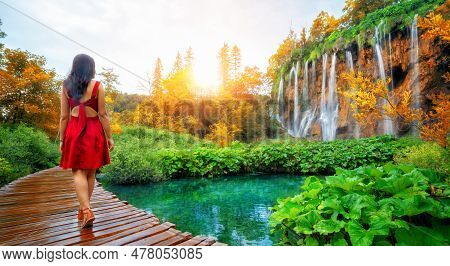 Woman Traveler Walking On Wooden Path Trail With Lakes And Waterfall Landscape In Plitvice Lakes Nat