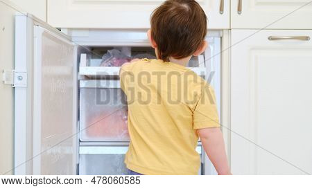 Opening The Fridge Can Be A Risk For Small Baby. The Little Caucasian Boy Is Happily Grabbing Food F