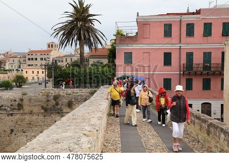 Alghero, Italy - May 29, 2023: People Take Part In A City Tour In Rainy Weather Alghero Town In Sard