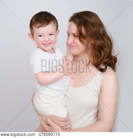 Happy Baby In The Arms Of A Mother Woman On A Studio White Background. Portrait Of A Smiling Child W