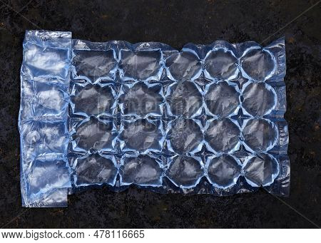 Plastic Bag With Water For Ice On A Dark Background. Blue Plastic Packaging Ice Bags For Home Water 