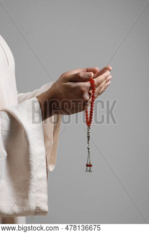 Muslim Woman With Misbaha Praying On Light Grey Background, Closeup