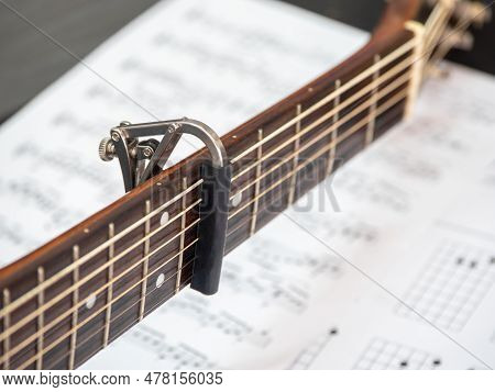 Capo On The Acoustic Guitar Neck , Capro Made From Aluminium, Selective Focus At Capo