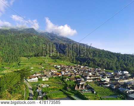 View Of Merbabu Mountain In Indonesia During Hazy Sunset With Green Village Foreground.