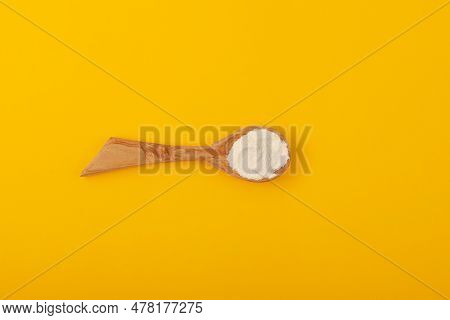 Xanthan Gum Powder In Wooden Spoon On Yellow Background, Top View. Food Additive E415. Suspending & 