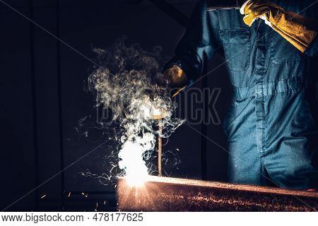 Metal Welder Working With Arc Welding Machine To Weld Steel At Factory While Wearing Safety Equipmen