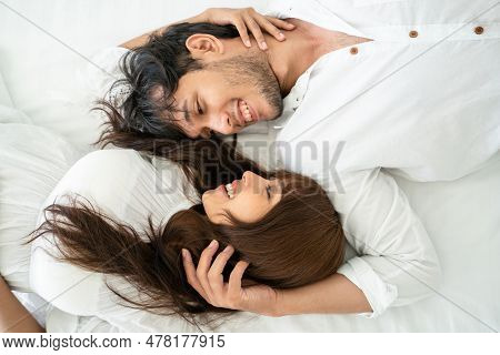 Happy Young Couple Relaxing In Home Bedroom After Waking Up In The Morning.