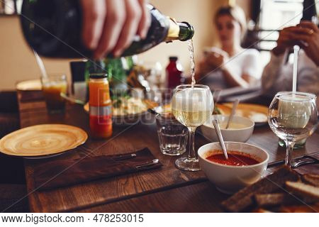 A Man Pours A Glass Of Champagne. Close Up Of Flowing Sparkling Wine. Dishes, Snacks, Plates, Sauces