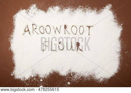 Arrowroot Flour Scattered On Brown Surface. Inscription Arrowroot Flour. Top View, Selective Focus.