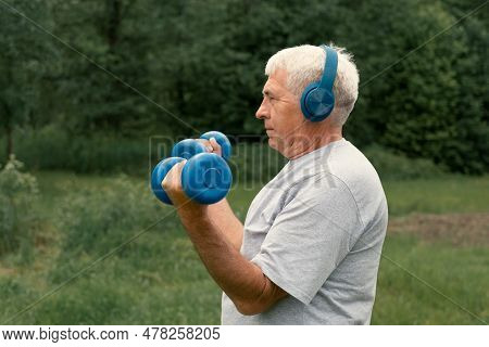 Senior Man Working Out Outdoors. Person Lifting Dumbbells. Old Male Exercising At Park. Healthy Peop