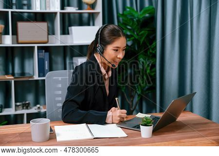 Asian Call Center With Headset And Microphone Working On Her Laptop. Female Operator Provide Excepti