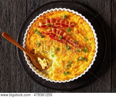 Cheddar Cheese Grits Casserole With Bacon Slices In Baking Dish With Spoon On Dark Wooden Table, Hor