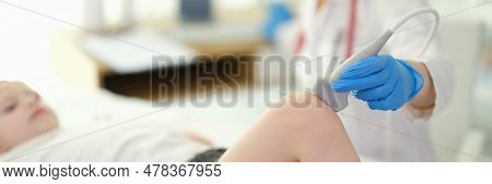 Doctor Rheumatologist Conducting Ultrasound Examination Of Child Knee In Clinic Closeup. Treatment O