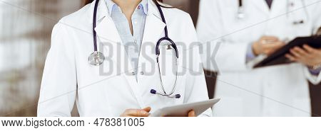 Unknown Woman Doctor Iusing Tablet Computer In Her Hands, While Standing In Clinic. Medicine Concept