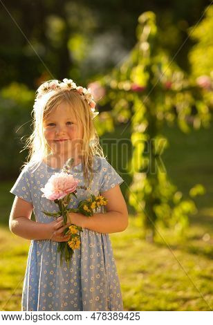 Cute Girl In Blue Dress And Flowers Wreath Holding Bouquet Of Flowers Infront Of Midsummer Pole On M