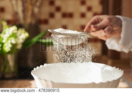 Girl Sieving Flour To The Plate For Cooking Tasty And Airy Bread. Wife Using Sieve For Flour In Cook
