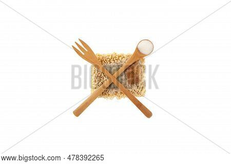 Dry Pressed Instant Noodles With Unhealthy Spices Are Abstractly Crossed Out With A Fork And Spoon. 
